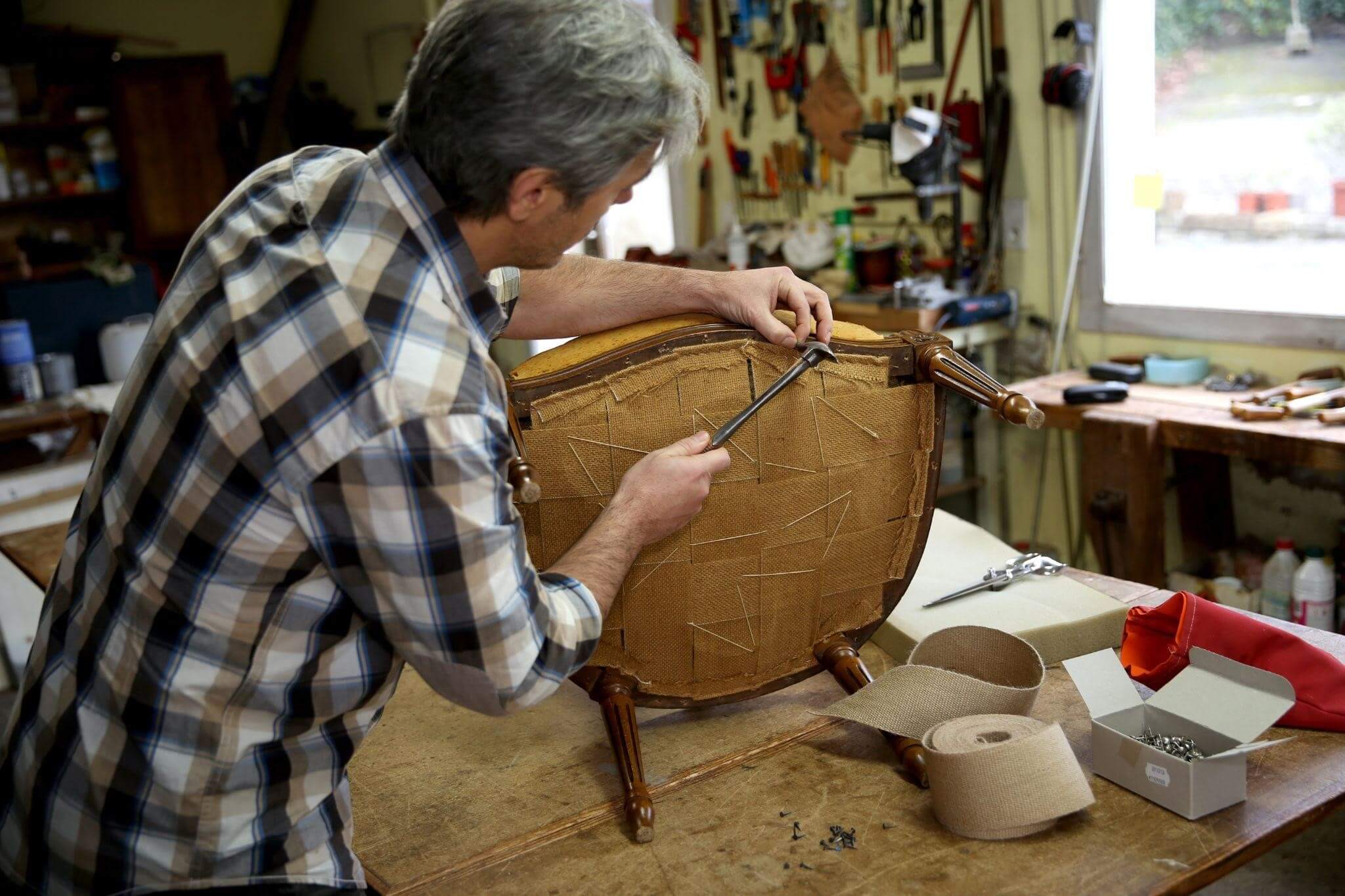 mester care repara un scaun de lemn in atelier