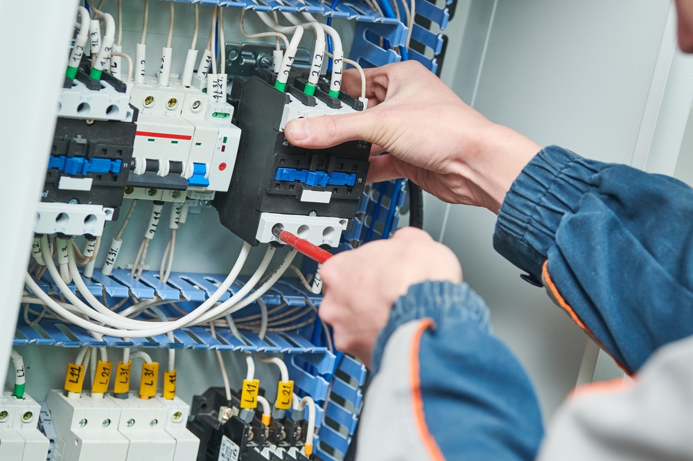 electrician care monteaza un contactor intr-un tablou electric