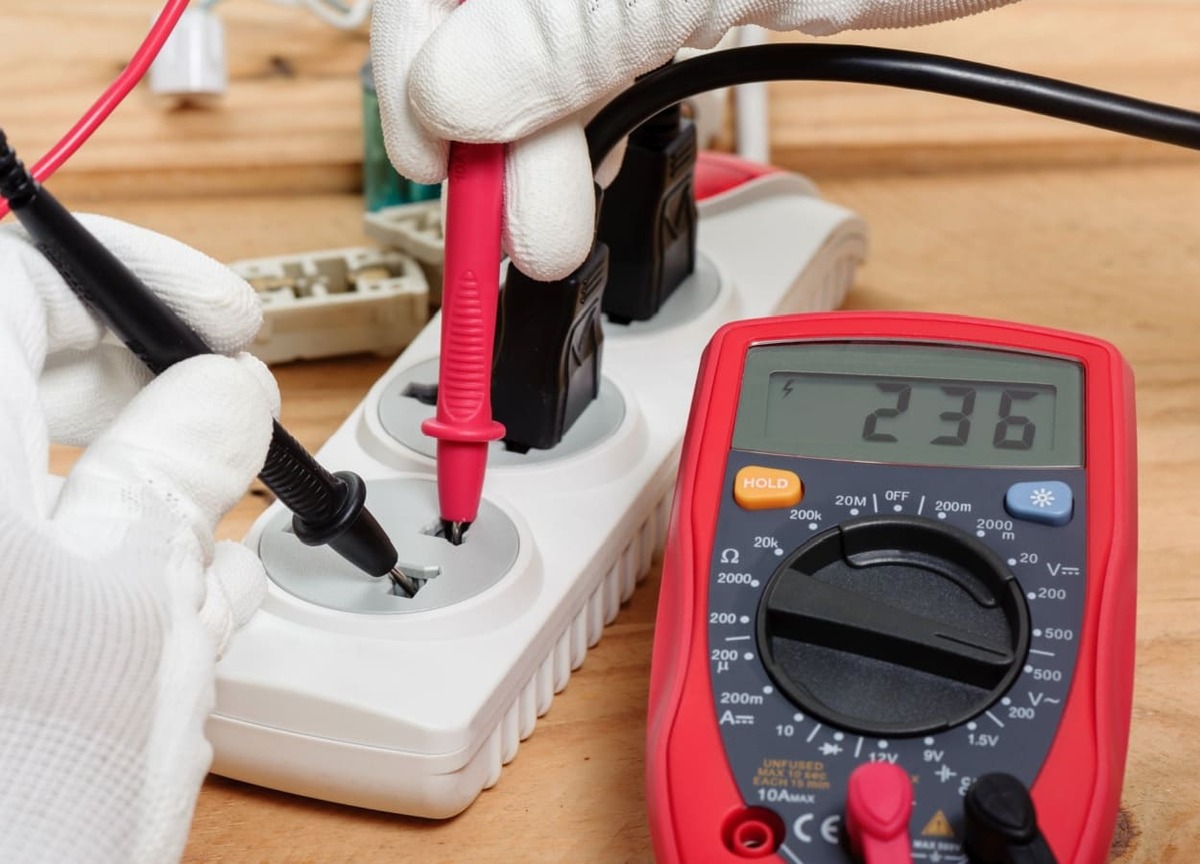 persoana care verifica tensiunea electrica folosind un multimetru