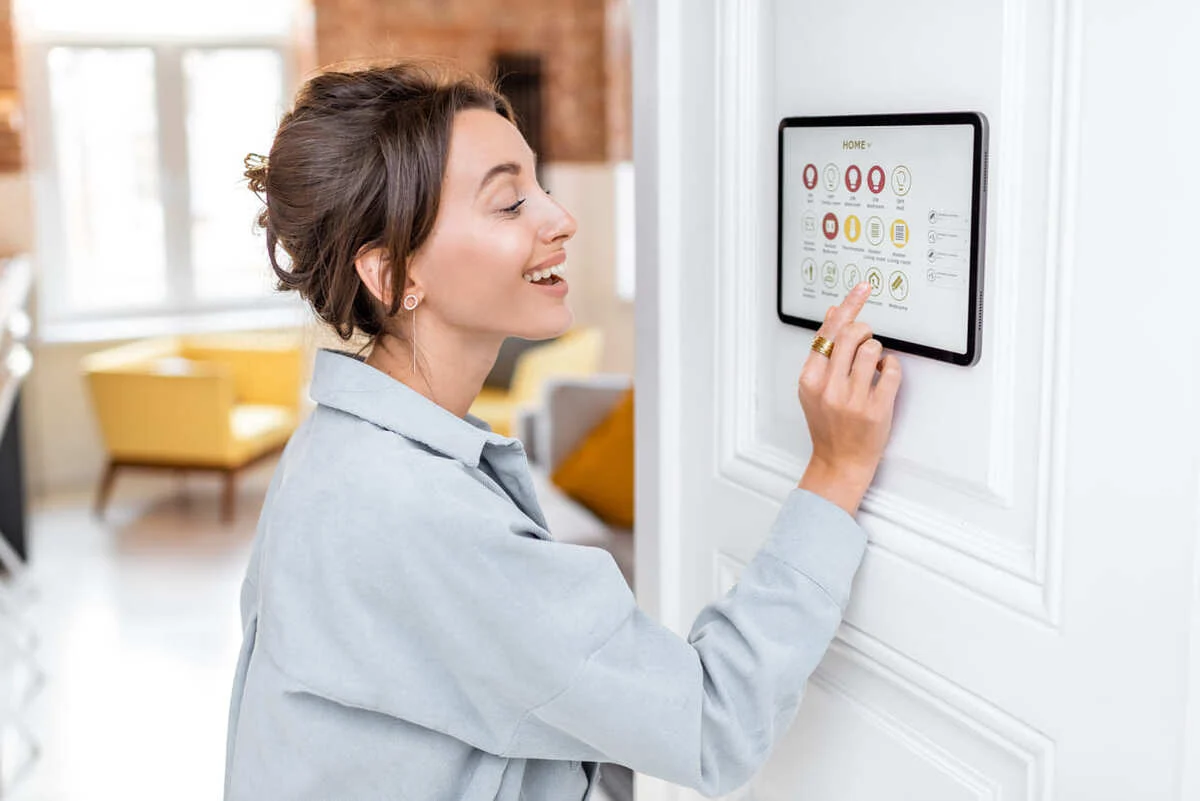 femeie zambitoare care acceseaza panoul de control al casei inteligente